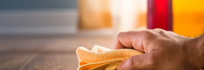 Hand reinigt Holzboden mit Tuch.